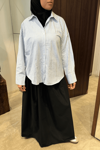 Chemise rayée bleu ciel Mayla Couture portée avec jupe noire — style pudique et élégant, coupe oversize fluide